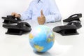 Globe and like hand with office phones on desk, global international support Royalty Free Stock Photo