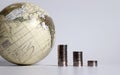 A globe and a pile of three coins.