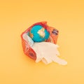 Globe, plastic bottle, blue surgical face mask and white glove in a nylon red bag. Golden background