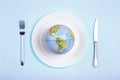 Globe on a plate for food on a blue background. Power, economy, politics, globalism, hunger, poverty and world food concept Royalty Free Stock Photo