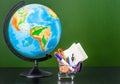 Globe with small shopping trolley with stationery near empty green chalkboard. Space for text Royalty Free Stock Photo