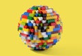 Globe or sphere of multicolored Lego blocks on yellow background