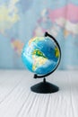 Globe on a wooden white table on the background of a world map. Royalty Free Stock Photo