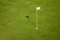 Glof flag mark in hole throwing shadow on the green course grass