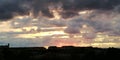 Gloomy autumn clouds over dark silhouettes of urban houses on a sunset background. Bright picturesque alarming exciting background