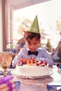 Gloomy boy feeling sad and looking at the birthday cake