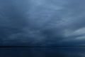 Gloomy dark blue overcast sky at thunderclouds at autumn dusk over calm water lake