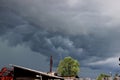 Gloomy gray sky hangs over green tree and old roof Royalty Free Stock Photo