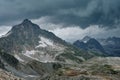 Gloomy mountain landscape with thunder cloudy sky, rocky ranges and peaks with glaciers and snow fields Royalty Free Stock Photo