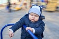 A gloomy pensive little boy rides a merry-go-round on the playground Royalty Free Stock Photo