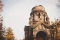 Gloomy statues, monuments, and gravestones of the cemetery on sunny autumn afternoon. Golden yellow twilight covering the trees. Royalty Free Stock Photo