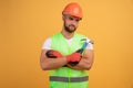 Gloomy unhappy male repairer has sad tired look, keeps hands crossed, holds hammer in hand, fatigue after repairing and manual