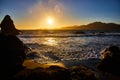 Glorious golden sunset over ocean waves rolling into shore with distant mountains Royalty Free Stock Photo