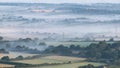 Glorious landscape image of layers of mist rolling over South Downs National Park English countryside during misty Summer sunrise Royalty Free Stock Photo