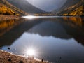 Sparkling sun with big sunburst reflecting off the lake in the autumn mountains Royalty Free Stock Photo