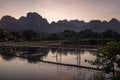 Glorious sunset over the mountains that dominate Vang Vieng overlooking the Nam Song river and the wooden bridge, Laos Royalty Free Stock Photo