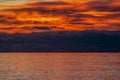 Glorious sunset over the sea with dark clouds on the horizon and red reflections on the rippling water Royalty Free Stock Photo