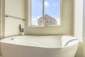Glossy bathtub and wall mounted towel rod inside a bathroom lit by sunlight