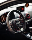 Glossy black leather steering wheel of a luxury Audi RS3 car.
