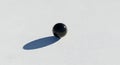 Glossy black sphere casting a long shadow on white concrete Royalty Free Stock Photo