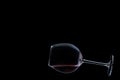 A glossy glass of red wine lies on black background with copy space