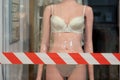 glossy mannequin of a woman in underwear in a closed store with a fenced off forbidden tape.