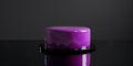 A glossy purple cake topped in the middle of a black surface, set against a dark background. The mood is elegant and