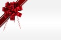 Glossy red bow is showing curled tails, angled stripes on white-gray gradient backdrop, copy space Royalty Free Stock Photo