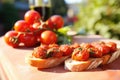 glossy, red cherry tomatoes on vine beside built bruschetta Royalty Free Stock Photo