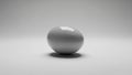 Glossy white egg is centrally positioned on a smooth light gray Royalty Free Stock Photo