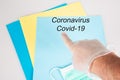 Glove plastic hand pointing finger on Novel coronavirus disease coid-19 virus written on blue folder on hospital desk