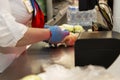 A gloved cashier in a supermarket scans the item. Close-up