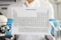 Gloved chemist holds periodic table of chemical elements closeup