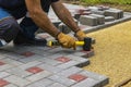 A gloved craftsman lays paving stones in layers. Brick paving slabs for professional use. Laying gray concrete paving slabs in the