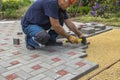 A gloved craftsman lays paving stones in layers. Brick paving slabs for professional use. Laying gray concrete paving slabs in the Royalty Free Stock Photo