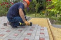 A gloved craftsman lays paving stones in layers. Brick paving slabs for professional use. Laying gray concrete paving slabs in the