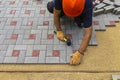 A gloved craftsman lays paving stones in layers. Brick paving slabs for professional use. Laying gray concrete paving slabs in the Royalty Free Stock Photo