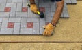 A gloved craftsman lays paving stones in layers. Brick paving slabs for professional use. Laying gray concrete paving slabs in the Royalty Free Stock Photo