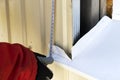 A gloved craftsman measures the window outside with a tape measure. Professional builder with a tool measures Royalty Free Stock Photo