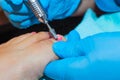 A gloved craftsman removes the nail polish from the toe plate with a milling cutter.