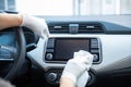 Gloved driver disinfecting the dashboard of a car with a rag for covid-19 prevention