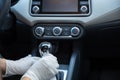 Gloved driver disinfecting the gearshift of a car with a rag for covid-19 prevention