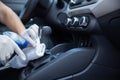 Gloved driver disinfecting the gearshift of a car with spray and rag for covid-19 prevention