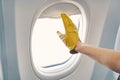 Gloved hand closing the window shades on the airplane