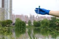 A gloved hand collects water into a test tube. Sampling from open water in a city water body. Scientist or biologist