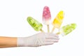 Gloved hand holding four fruit popsicles. Concept of summer season