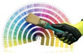 Gloved Hand Holding a Paintbrush with Pantone Color Swatches on Background Royalty Free Stock Photo