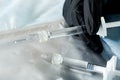 Gloved hand holding a syringe with cosmetic injection on a grey background. Plastic and aesthetic surgery