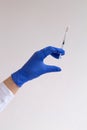 Gloved hand holding a syringe on grey background. Royalty Free Stock Photo