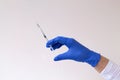 Gloved hand holding a syringe on grey background. Royalty Free Stock Photo